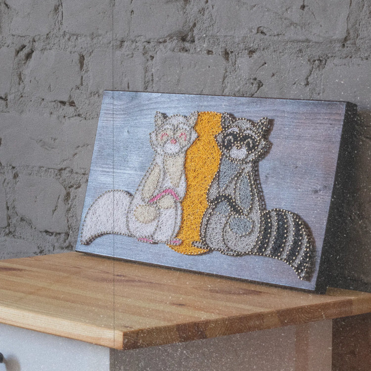 string art sign with 2 raccoons