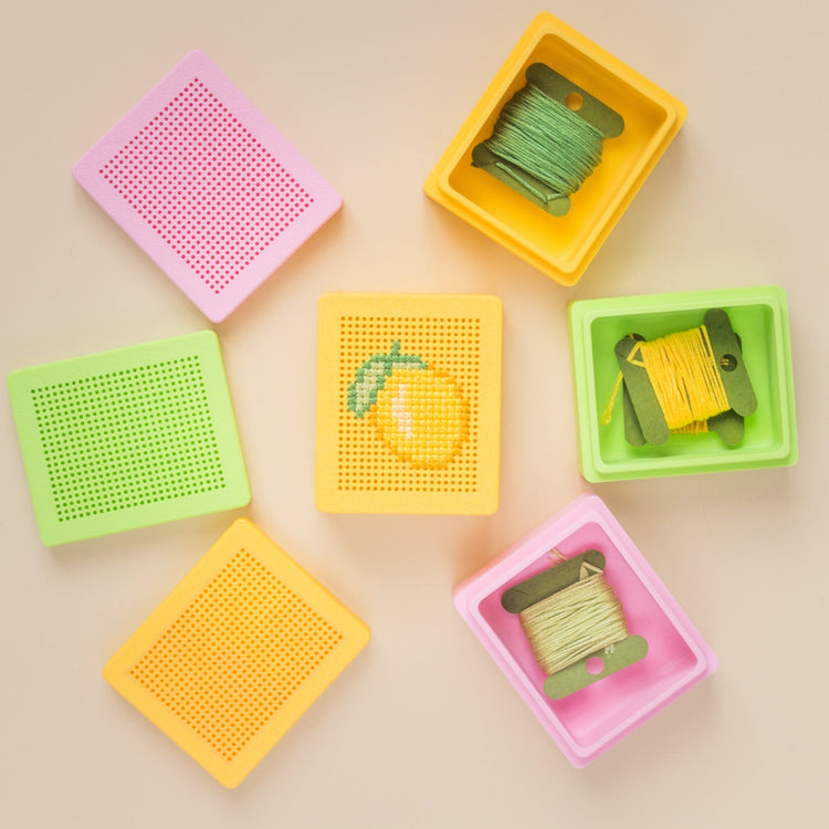 Colorful cross stitch bases and stitchable boxes with embroidery thread, designed for modern embroidery and beginner cross stitch projects.