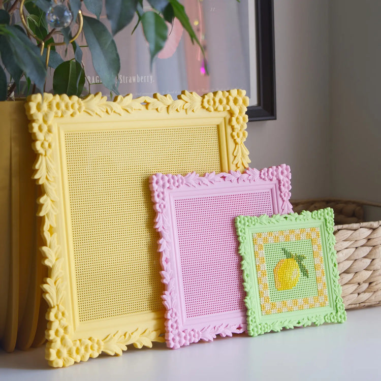 Floral cross stitch frames in yellow, pink, and green, shown in Large, Medium, and Small with a finished lemon design in the smallest frame.
