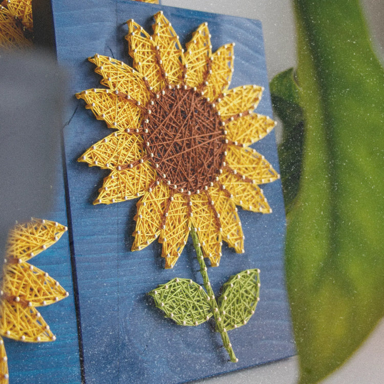 string art sunflower sign on a blue wood base with green stem