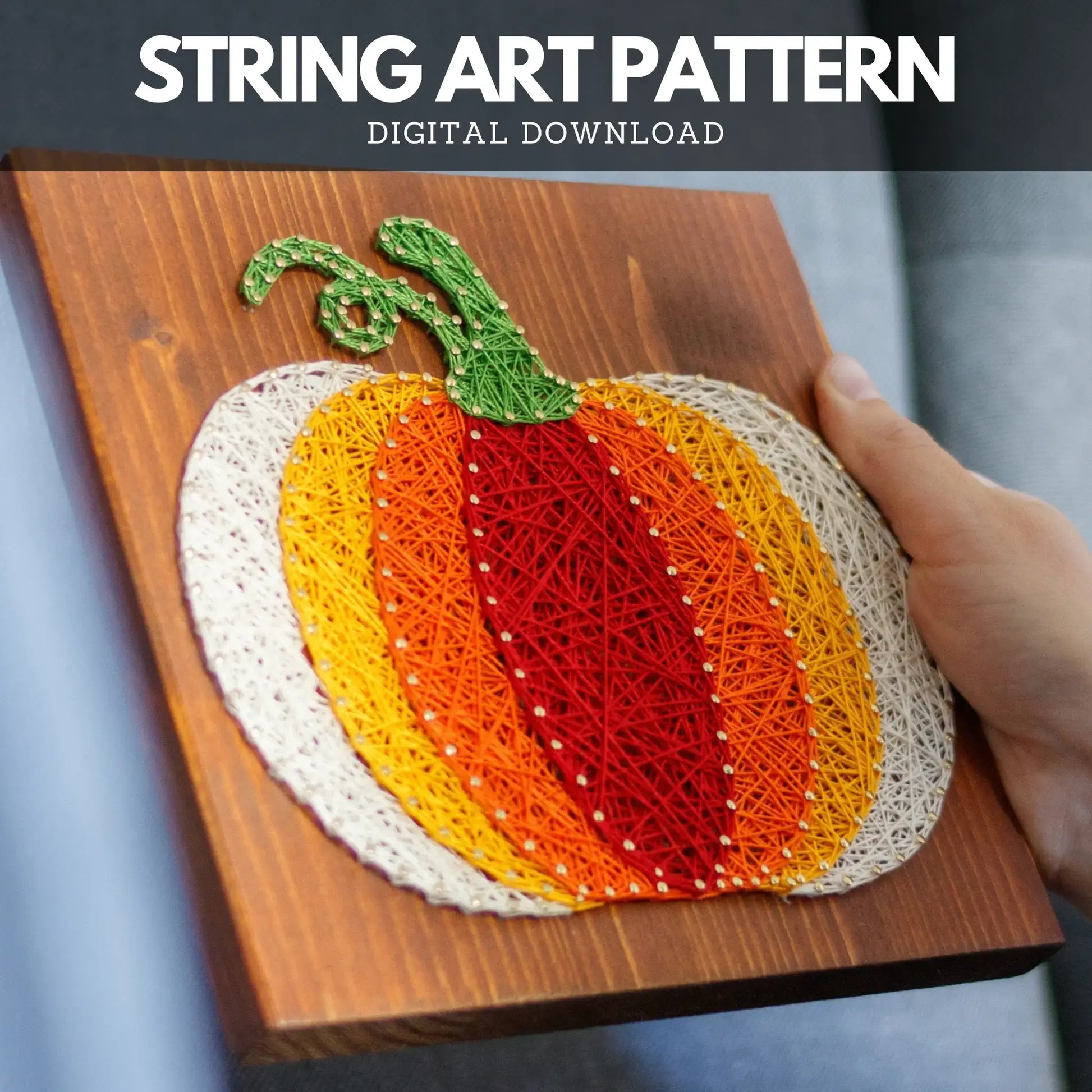 The finished pumpkin string art pattern held by a hand, displaying a textured, handmade design ready to be hung or displayed as a fall decoration.