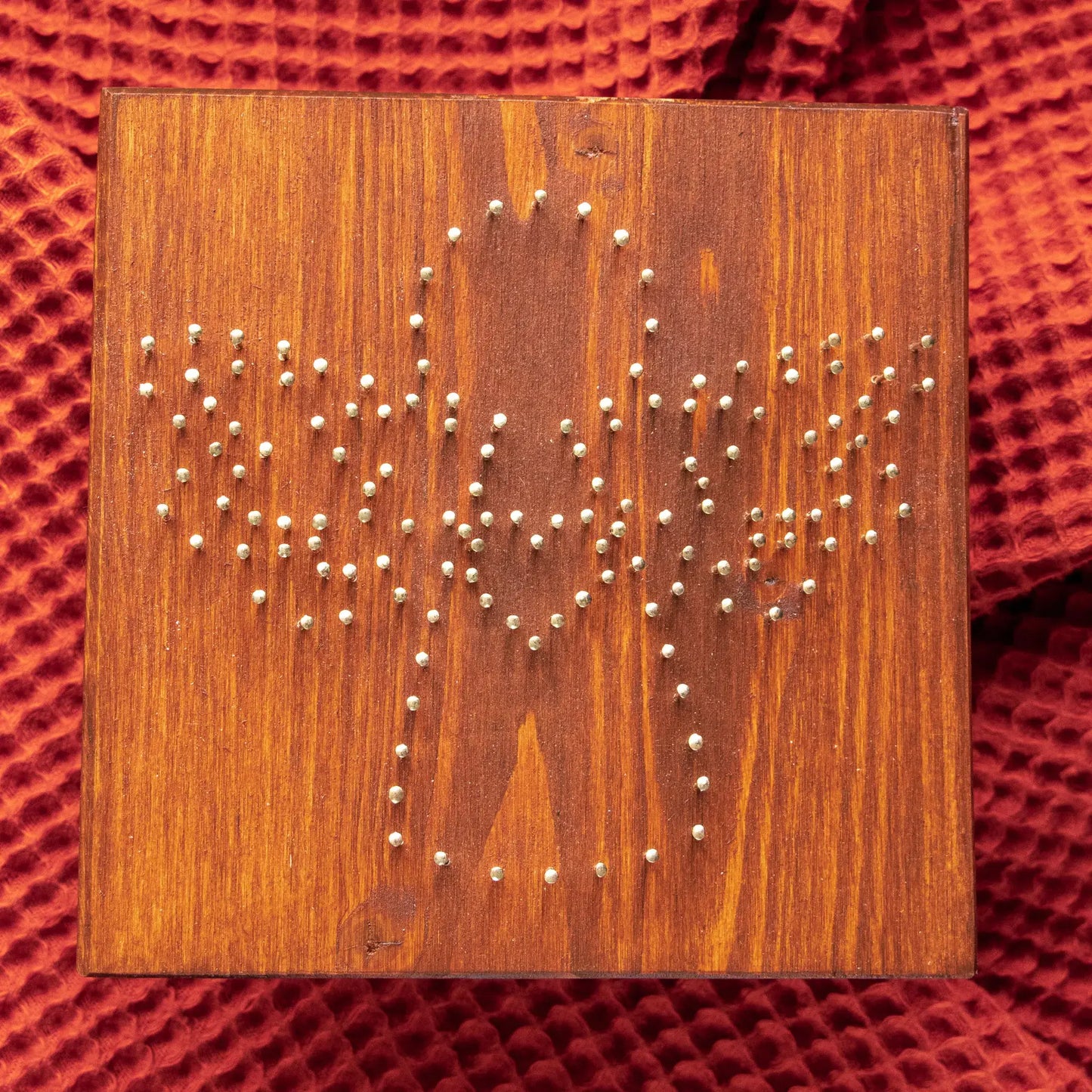 Wood board with pre-nailed outline for angel string art pattern, nail placement preview.