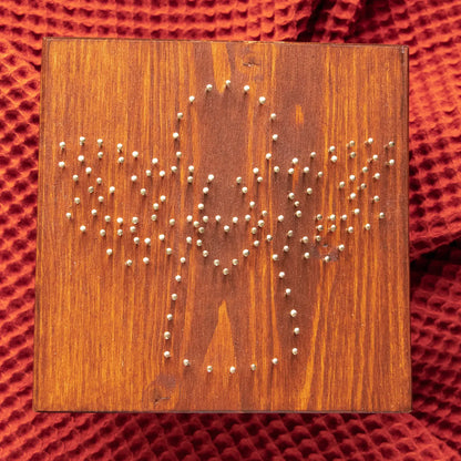 Wood board with pre-nailed outline for angel string art pattern, nail placement preview.