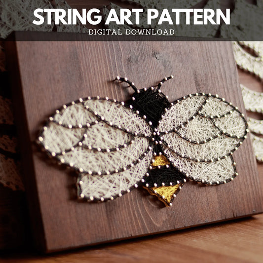 Bee string art pattern highlighted on a wooden base, showcasing a black body, white wings, and yellow accents for a vibrant look.
