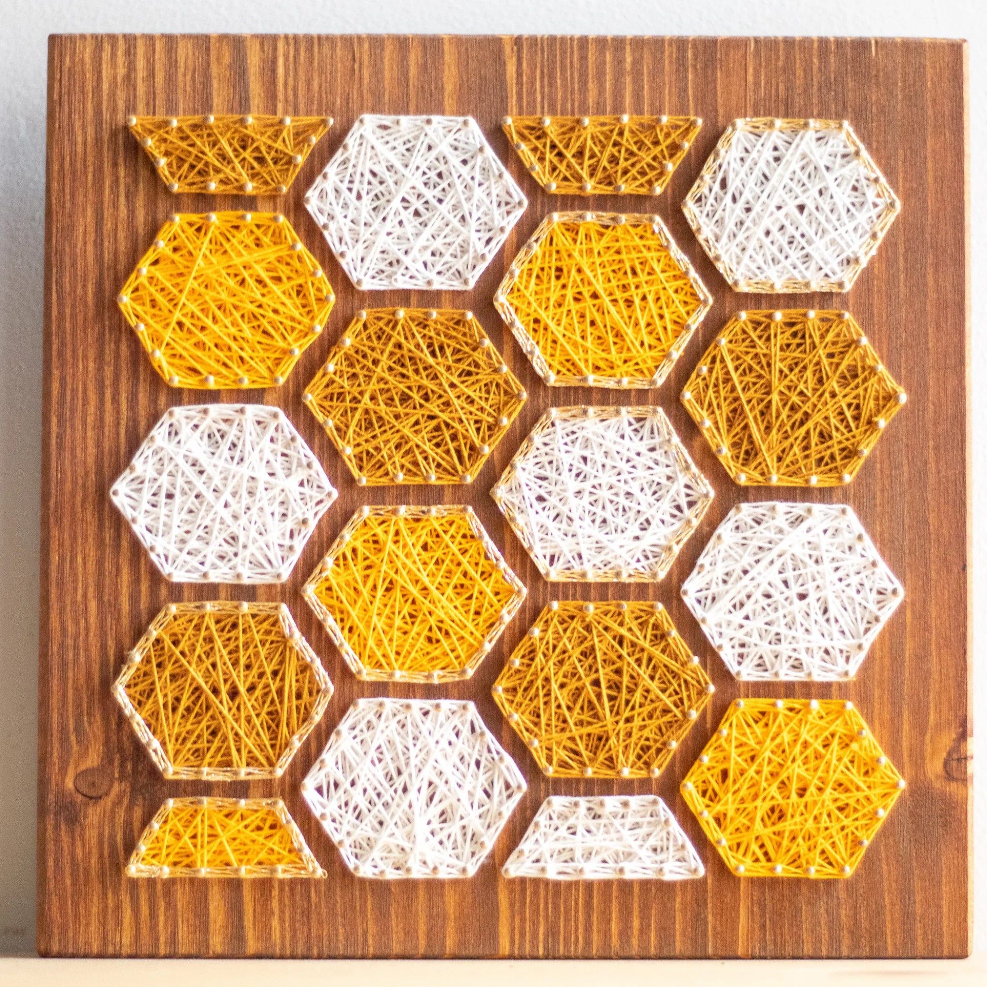 front view - Bee honeycombs string art pattern featuring hexagonal designs in yellow and white thread on a wooden base. Available as a digital download for crafting enthusiasts.