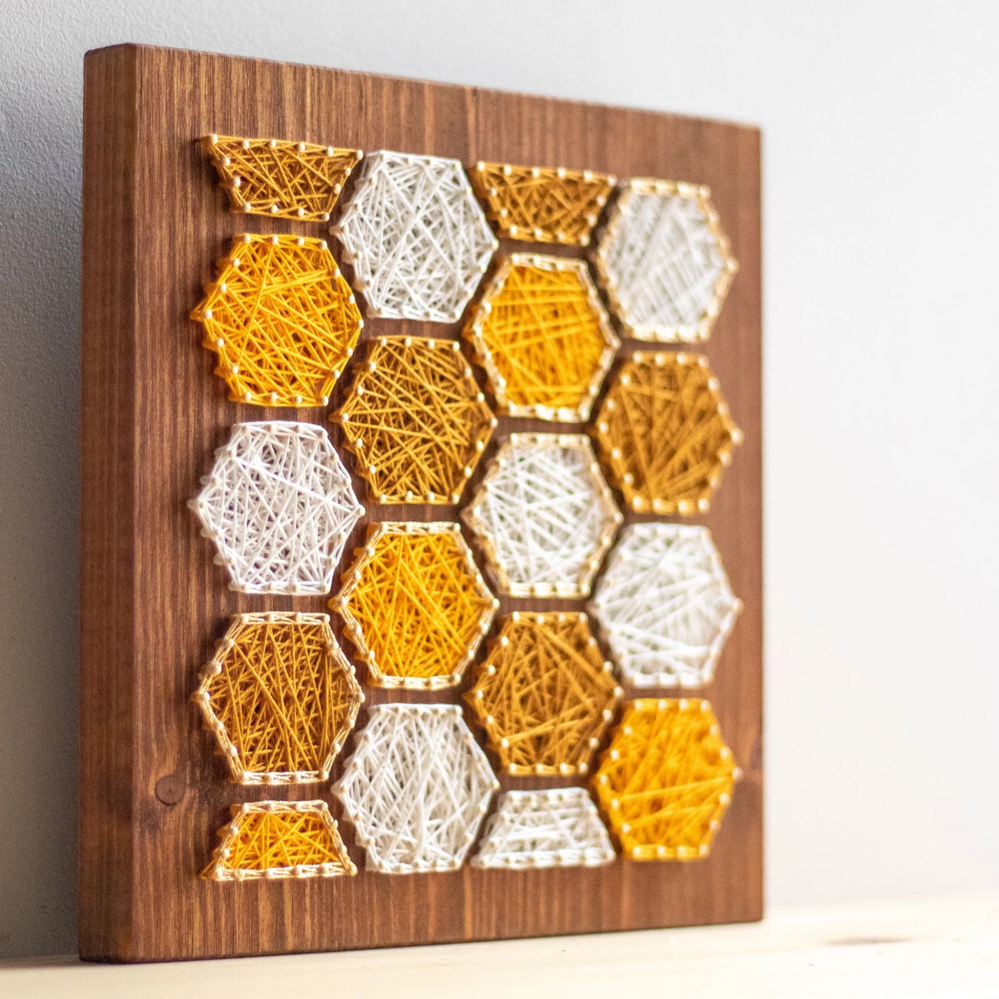 side view - Bee honeycombs string art pattern featuring hexagonal designs in yellow and white thread on a wooden base. Available as a digital download for crafting enthusiasts.