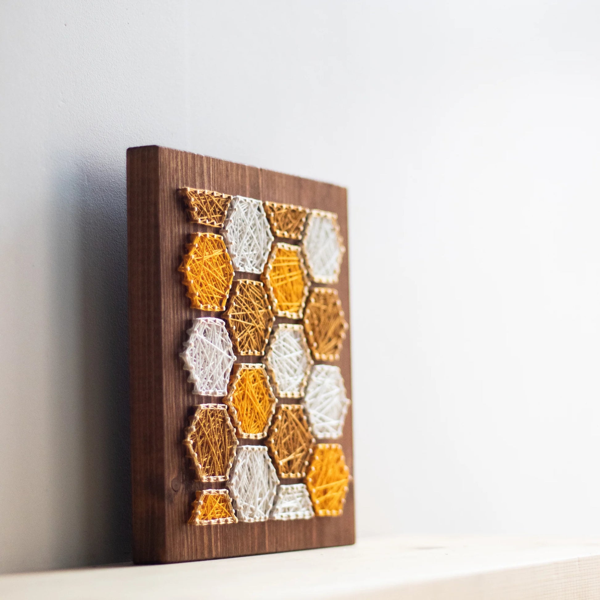 side view- Bee honeycombs string art pattern featuring hexagonal designs in yellow and white thread on a wooden base. Available as a digital download for crafting enthusiasts.