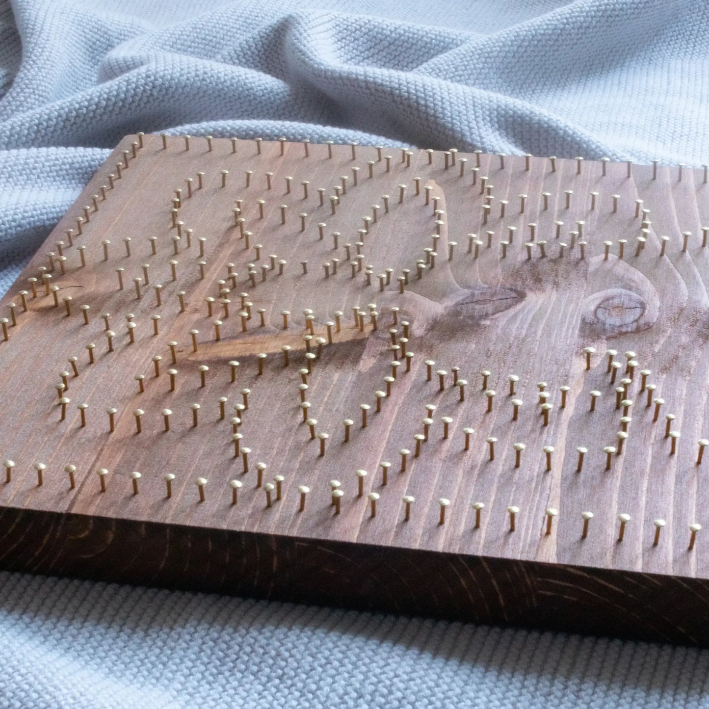 In process. Buddha silhouette string art with vibrant lotus petals in pink, orange, and white, mounted on a wooden background, representing a peaceful, meditation-inspired design.