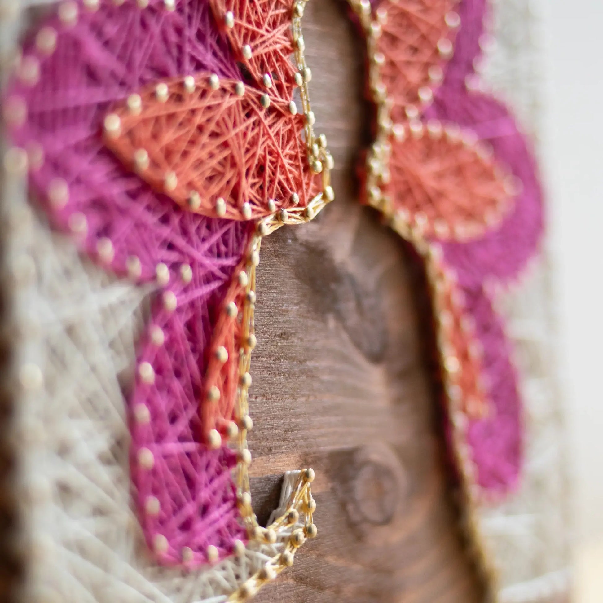 Detailed view. Buddha silhouette string art with vibrant lotus petals in pink, orange, and white, mounted on a wooden background, representing a peaceful, meditation-inspired design.