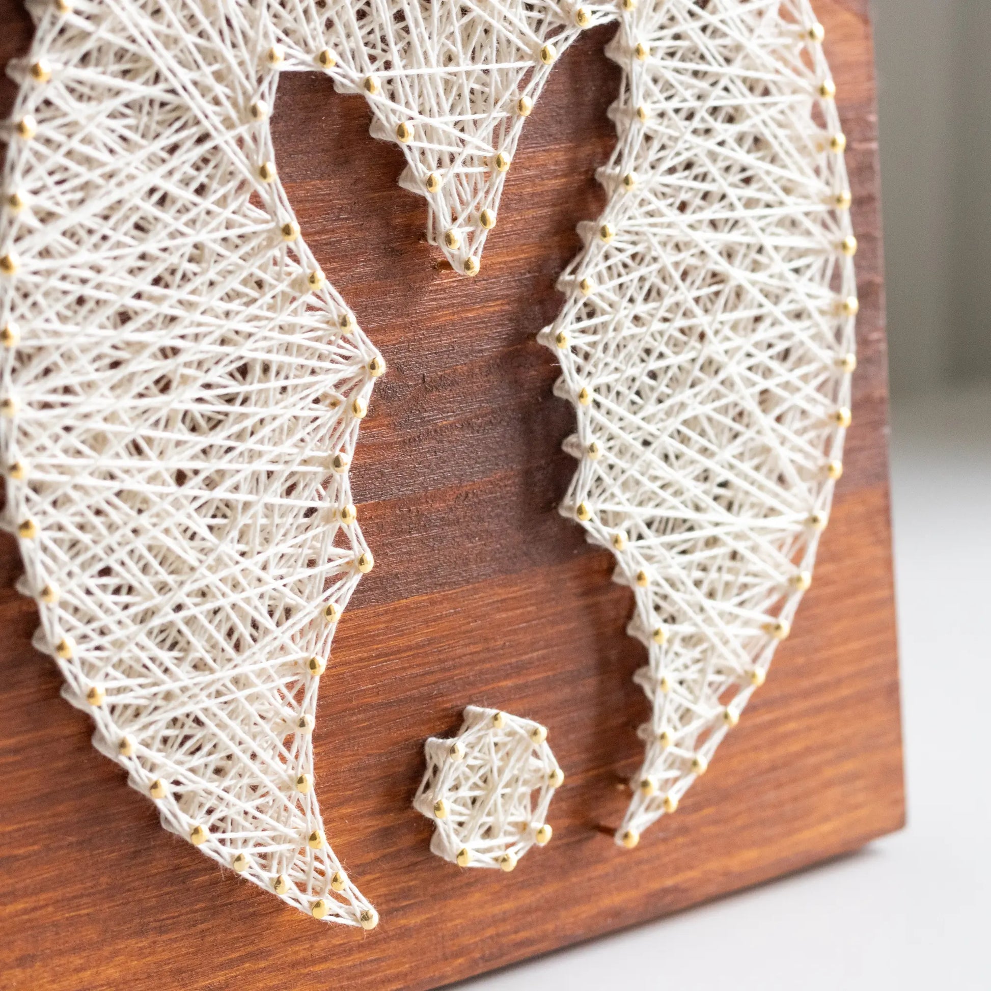 bunny silhouette string art sign made with gold color nails on a brown wood base