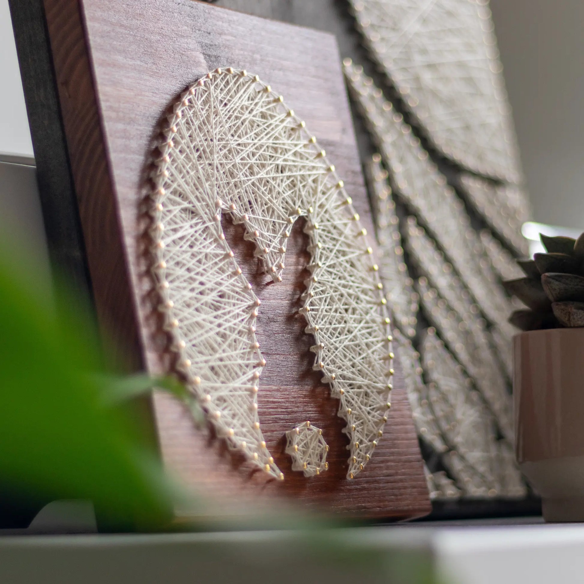 bunny silhouette string art sign made with gold color nails on a brown wood base