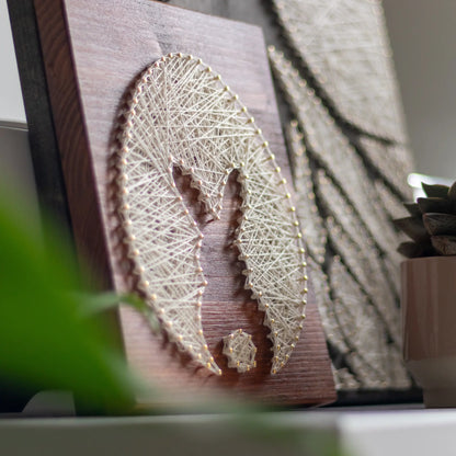 bunny silhouette string art sign made with gold color nails on a brown wood base