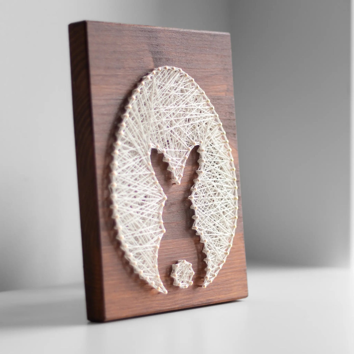 bunny silhouette string art sign made with gold color nails on a brown wood base