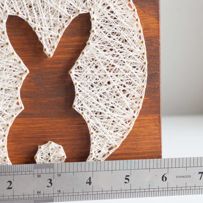 Close-up of the bunny and egg string art pattern with a ruler next to it, showing the size and detail.