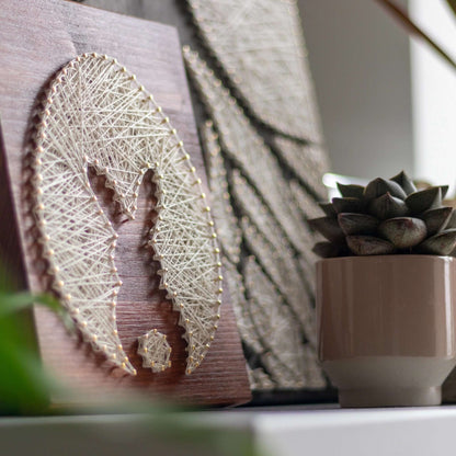 Bunny and egg string art displayed on a shelf next to a succulent, highlighting its use as home decor.