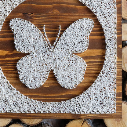 Close-up of butterfly string art, highlighting detailed white string pattern on brown wood, perfect for craft kits for adults.