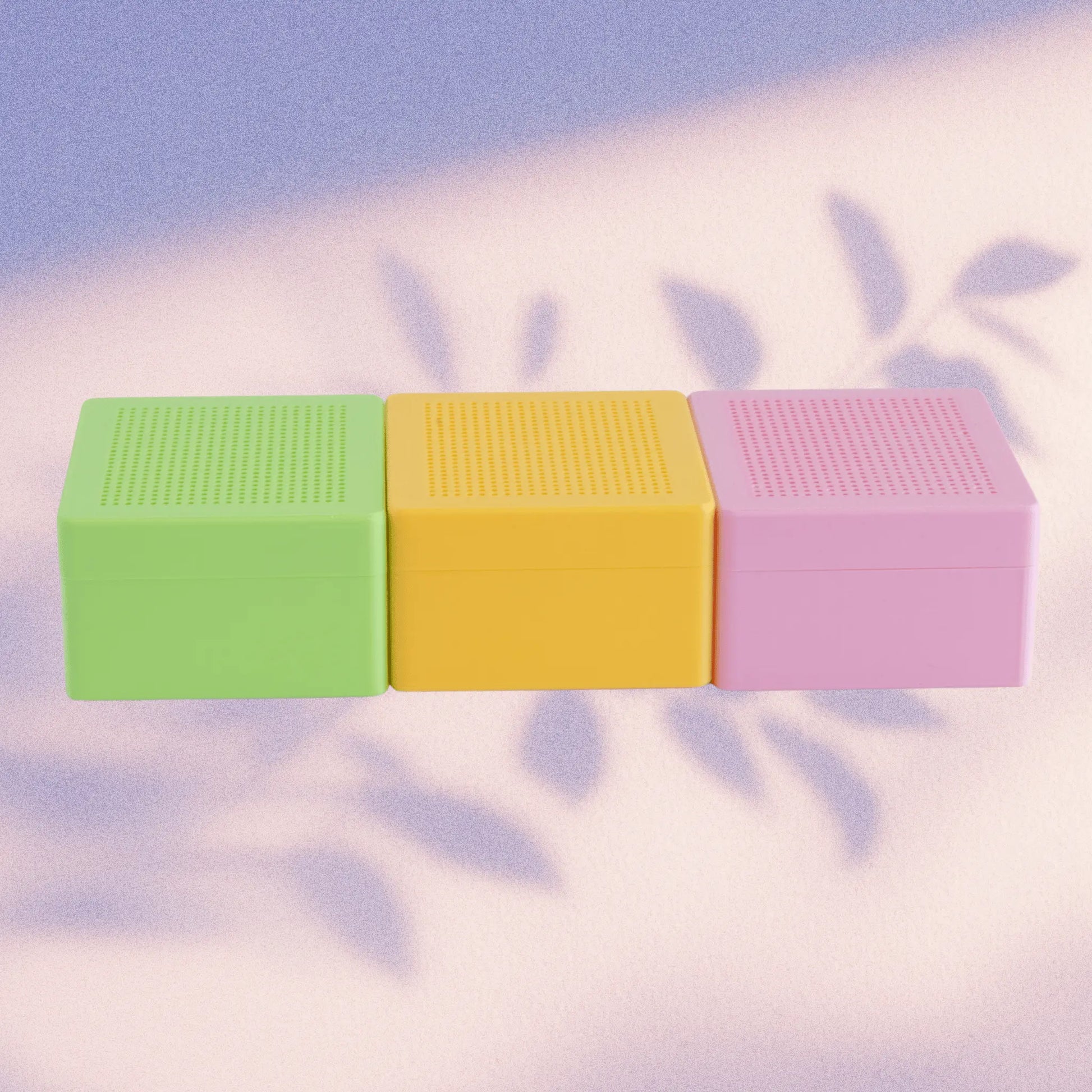 Set of three stitchable cross stitch boxes in green, yellow, and pink with blank grid lids, shown side by side