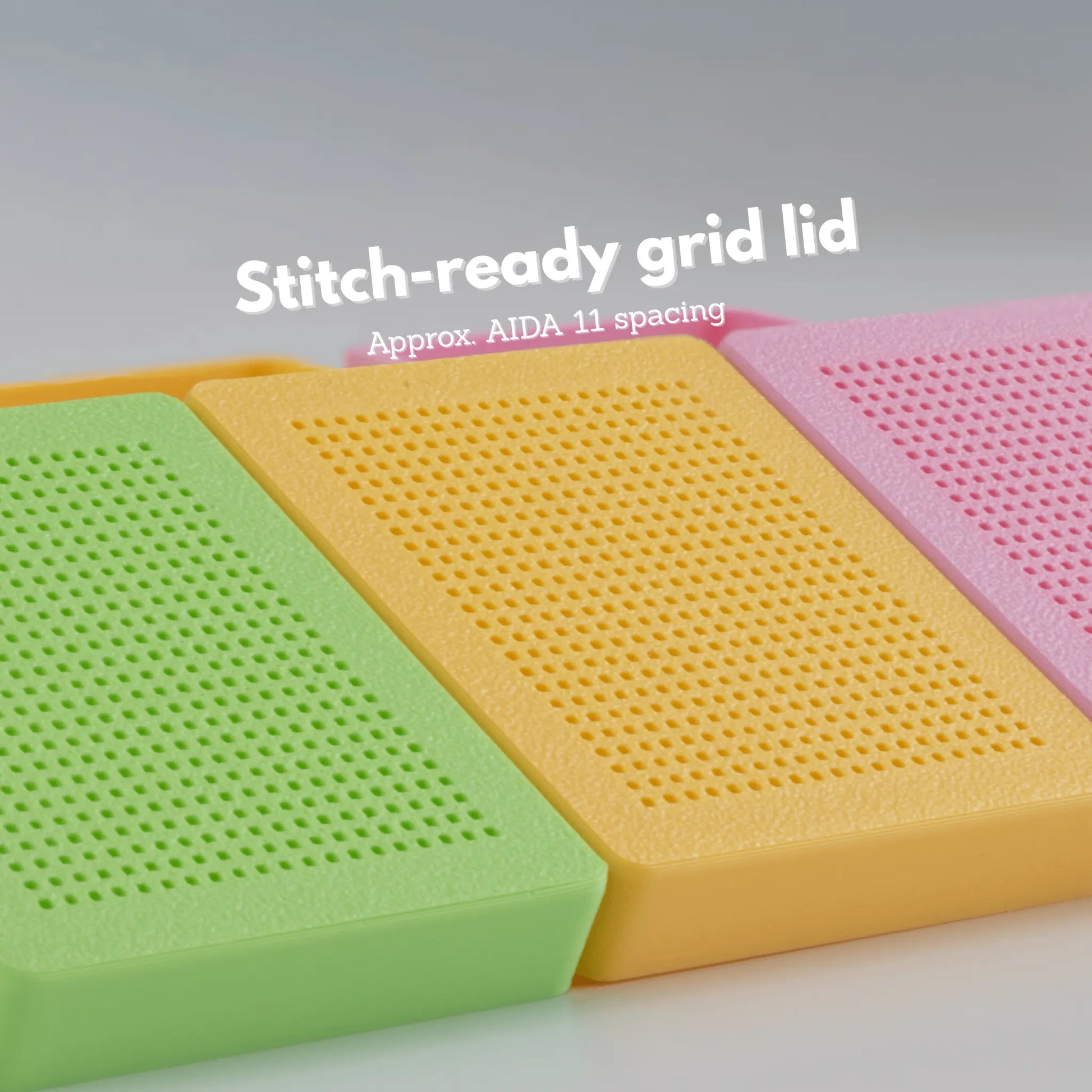 Close-up of stitchable grid lids on colorful cross stitch boxes, showing evenly spaced holes similar to AIDA 11 fabric, designed for cross stitch and hand embroidery projects.