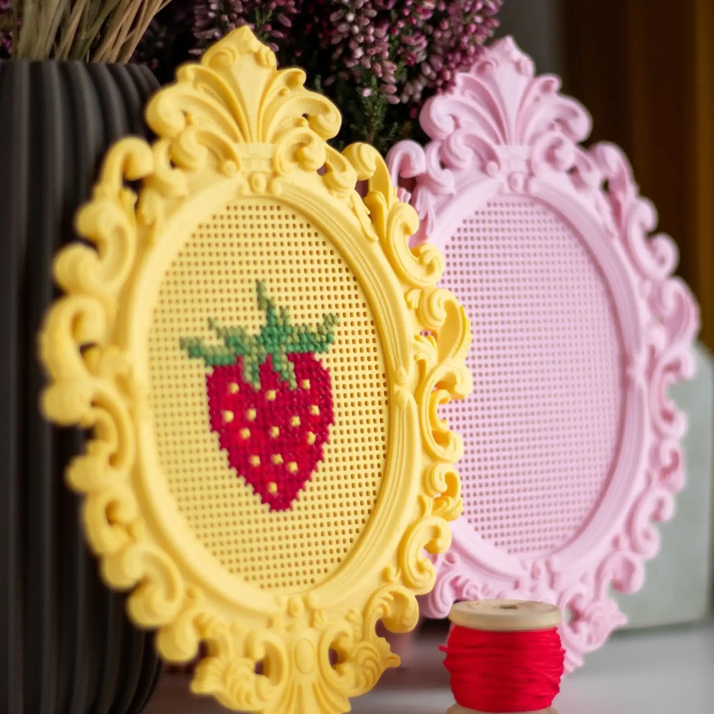 Set of two stitchable cross stitch frames, showing a yellow frame with a finished strawberry cross stitch and a pink blank frame ready for stitching.