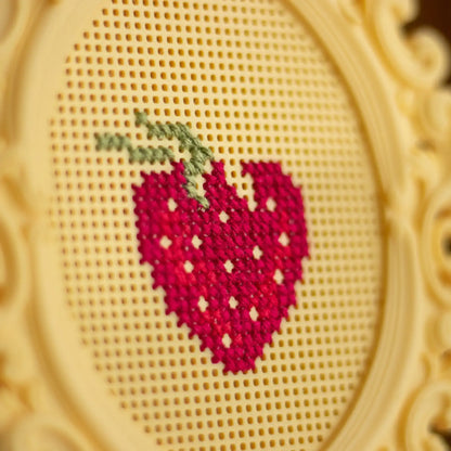 Close-up of a strawberry cross stitch design stitched onto a stitchable cross stitch frame, showing the grid structure and stitch detail.