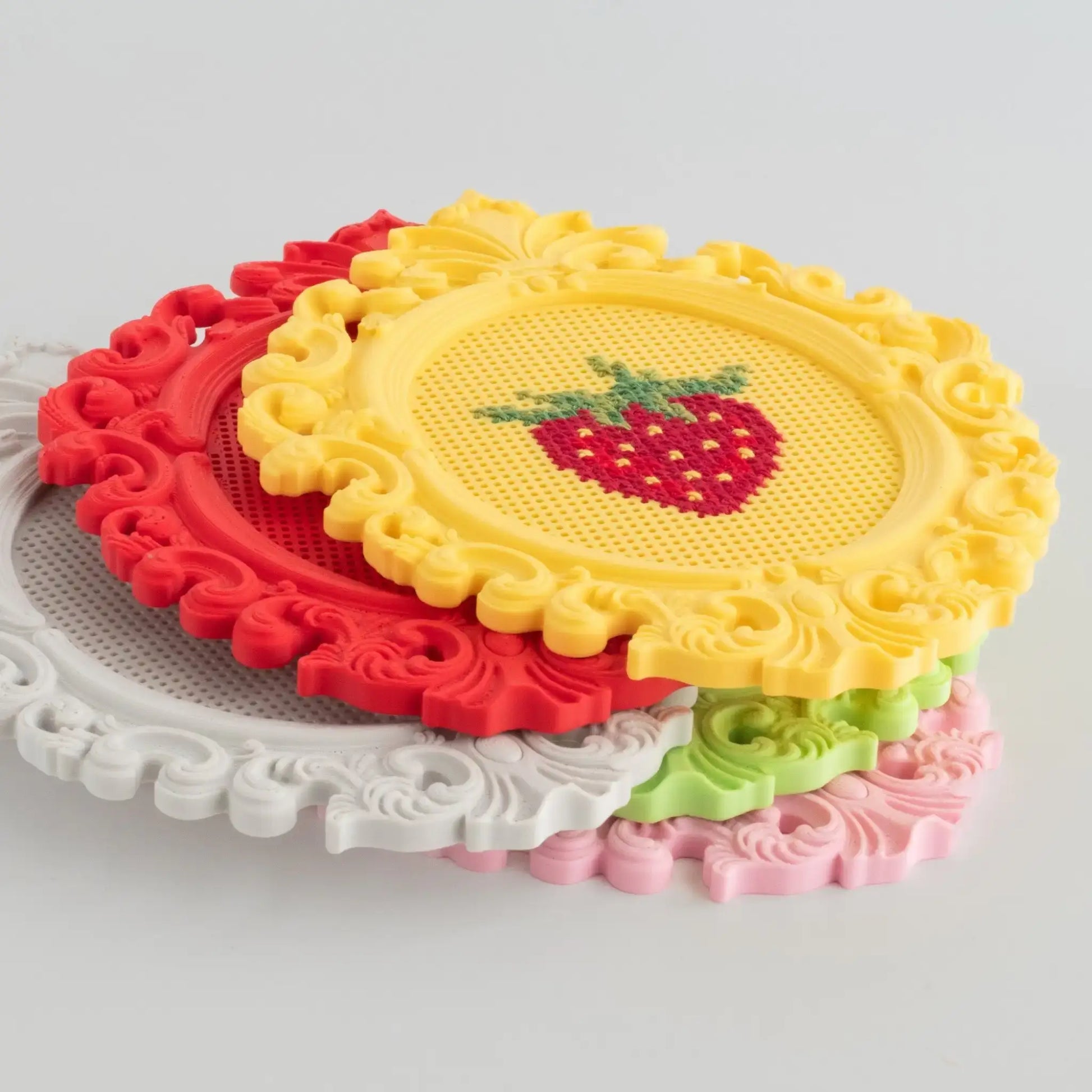 Stacked stitchable cross stitch frames in multiple colors, showing the frame thickness and raised decorative edges.