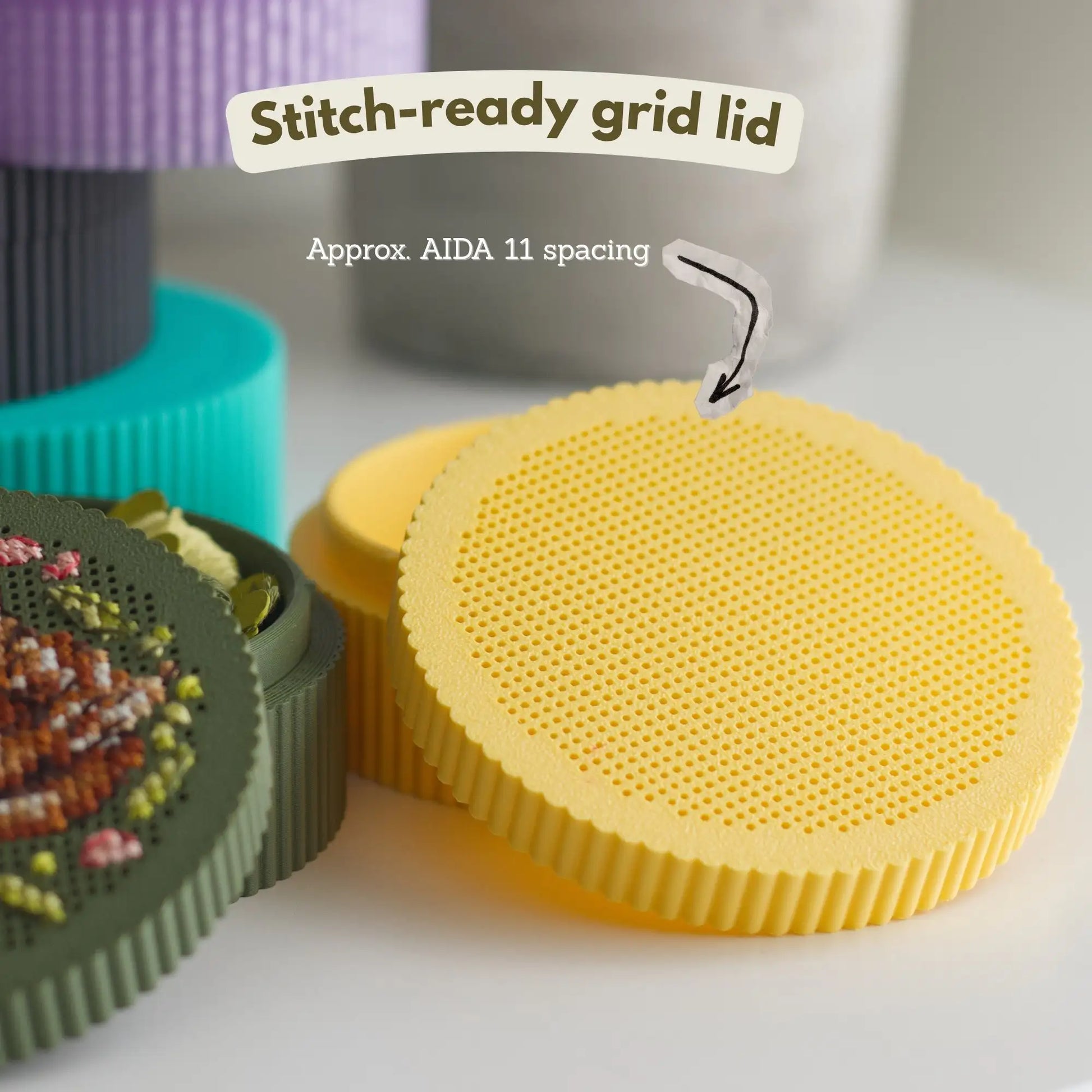 Stitch-ready perforated grid lid in yellow showing approximate AIDA 11 spacing, beside dark green stitched fawn lid