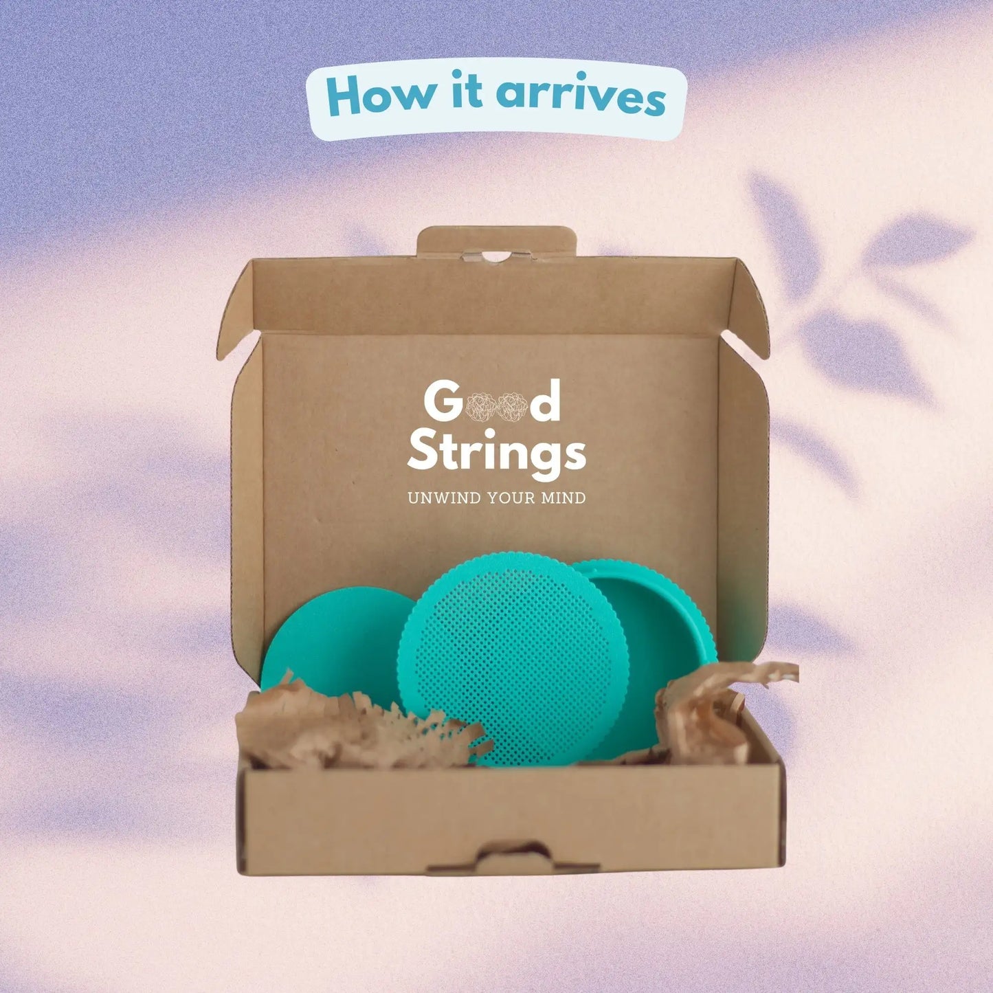 How the round cross stitch box arrives — teal stitchable box with perforated lid in branded GoodStrings cardboard packaging with recycled paper fill
