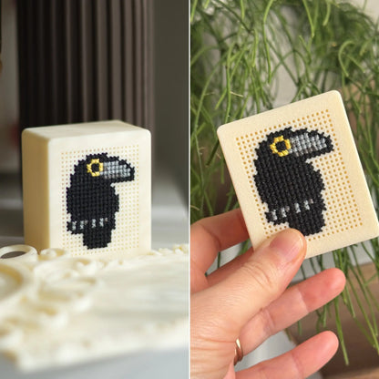 Cream stitchable cross stitch box with black raven design, shown displayed and held in hand