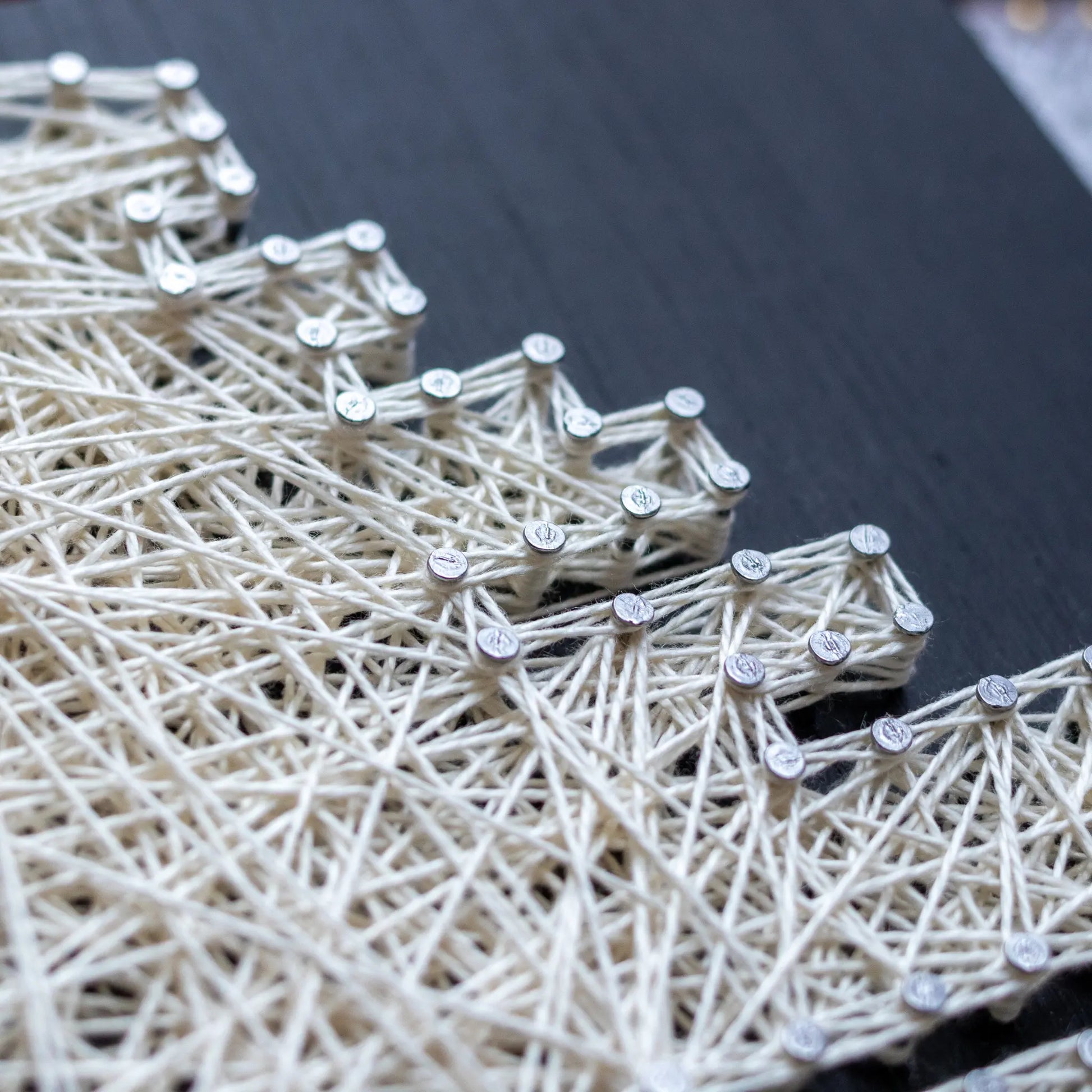 DIY string art kit featuring a Death Star design with white threads on a black wooden board by GoodStrings - details shot