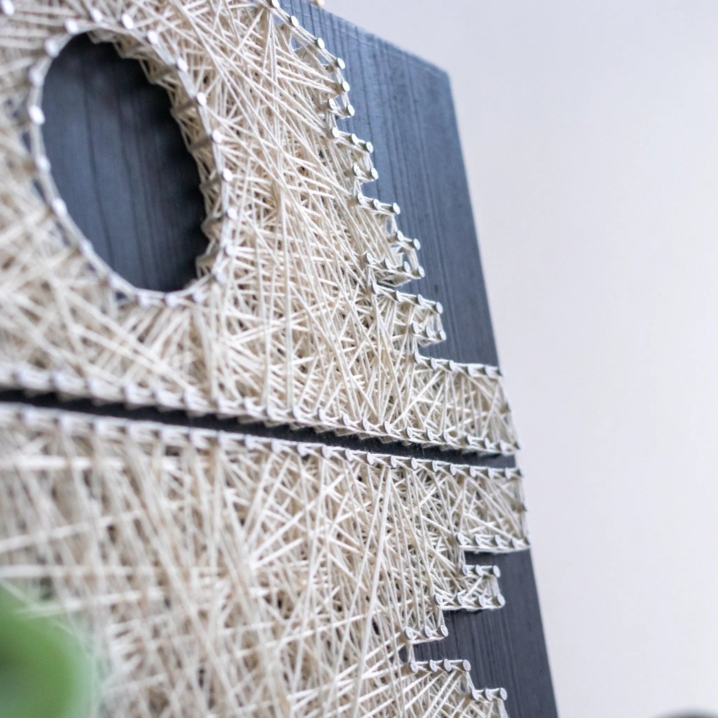 DIY string art kit featuring a Death Star design with white threads on a black wooden board by GoodStrings - details from side, basic nails