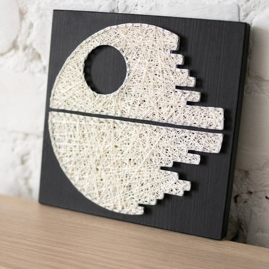 DIY string art kit featuring a Death Star design with white threads on a black wooden board by GoodStrings side view