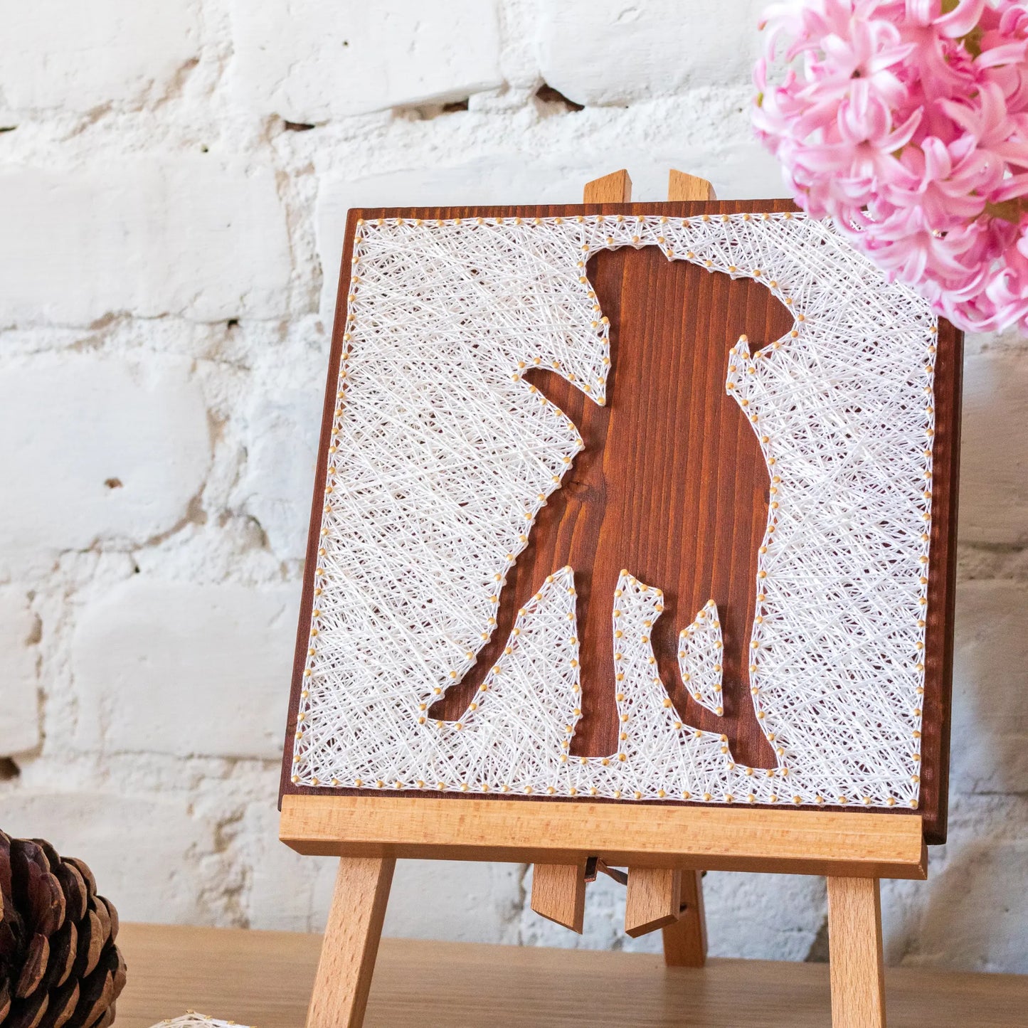 DIY string art kit featuring a dog silhouette outlined with white thread on a rustic wooden board by GoodStrings - standing on table