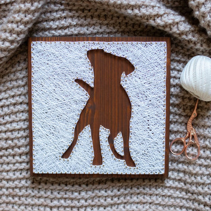 DIY string art kit featuring a dog silhouette outlined with white thread on a rustic wooden board by GoodStrings - view from top