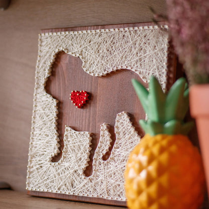 DIY string art kit featuring a dog silhouette with a red heart outlined with ivory thread on a rustic wooden board by GoodStrings - side view