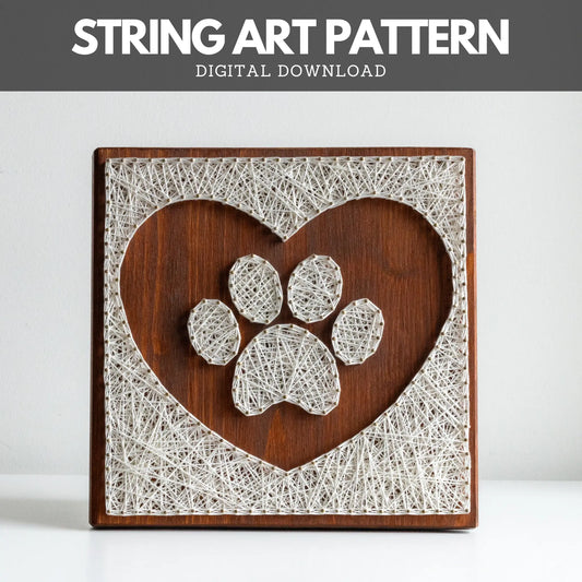 String art pattern featuring a paw print design inside a heart shape. The artwork is made using white string on a wooden board, creating a minimalist, rustic look. This digital download pattern allows you to create a similar piece at home.