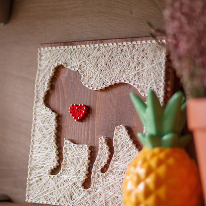 side view. Completed dog silhouette with heart string art design on a wooden board, crafted using GoodStrings' beginner-friendly string art pattern. Features a white thread outline of a dog with a heart detail, perfect for DIY home decor.