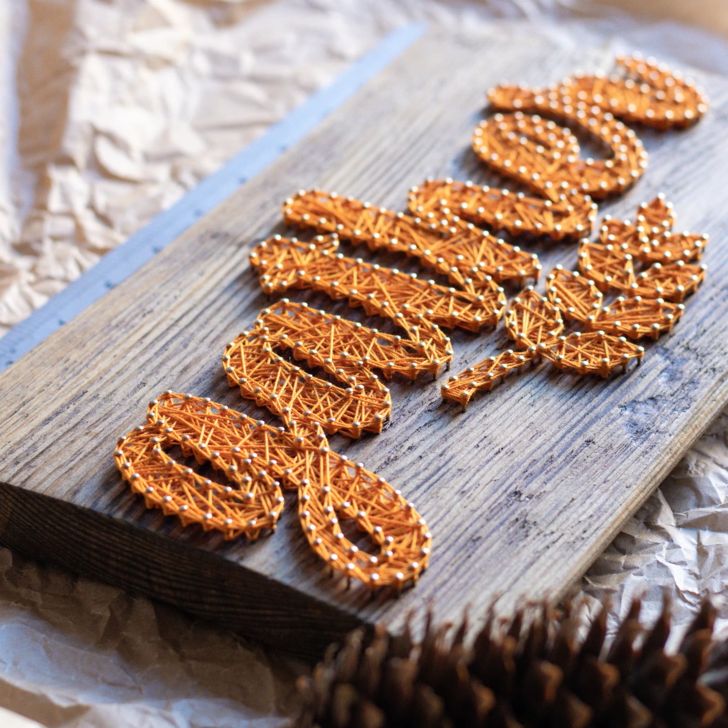 Side view of the 'Gather' fall sign string art design. The yellow string art pattern stands out on the weathered wood, showcasing the intricate details of the handmade craft.