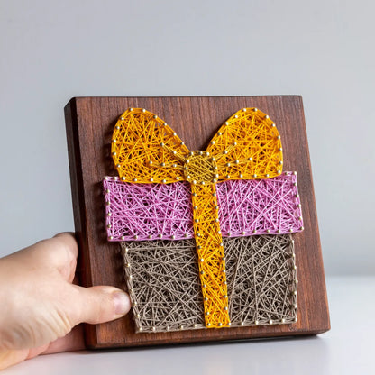 DIY Gift Box String Art Kit with pre-nailed wooden base in yellow, pink, and brown threads, handmade craft for adults.
