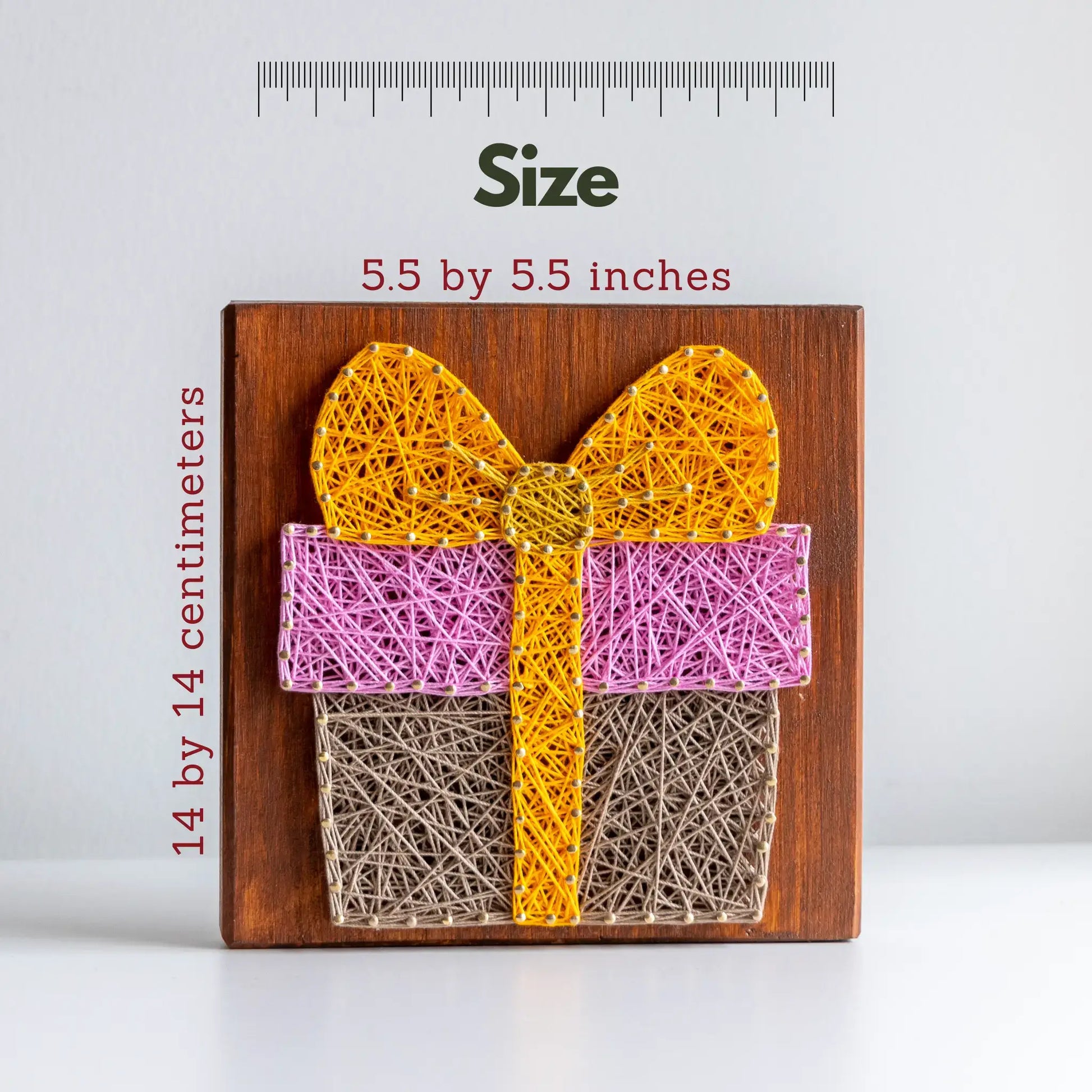 String art of a gift box with a yellow bow on a wooden board, accompanied by size measurements.