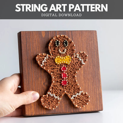 String art pattern of a gingerbread man on a wooden board with a hand holding it.