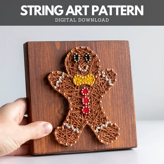 String art pattern of a gingerbread man on a wooden board with a hand holding it.