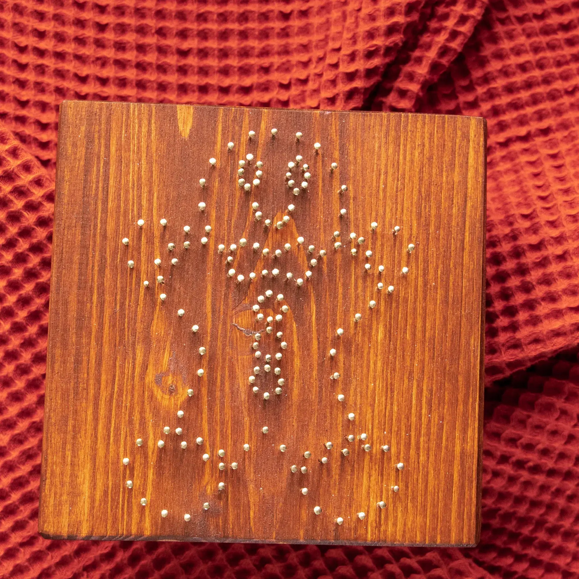 Wood board with pre-nailed outline for gingerbread man string art pattern, nail placement preview.