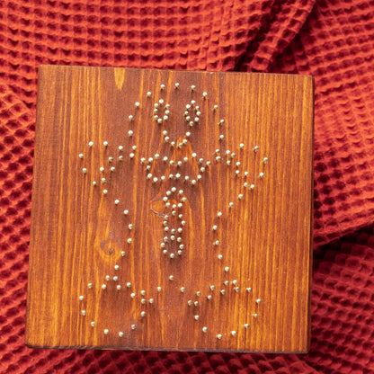 Wood board with pre-nailed outline for gingerbread man string art pattern, nail placement preview.