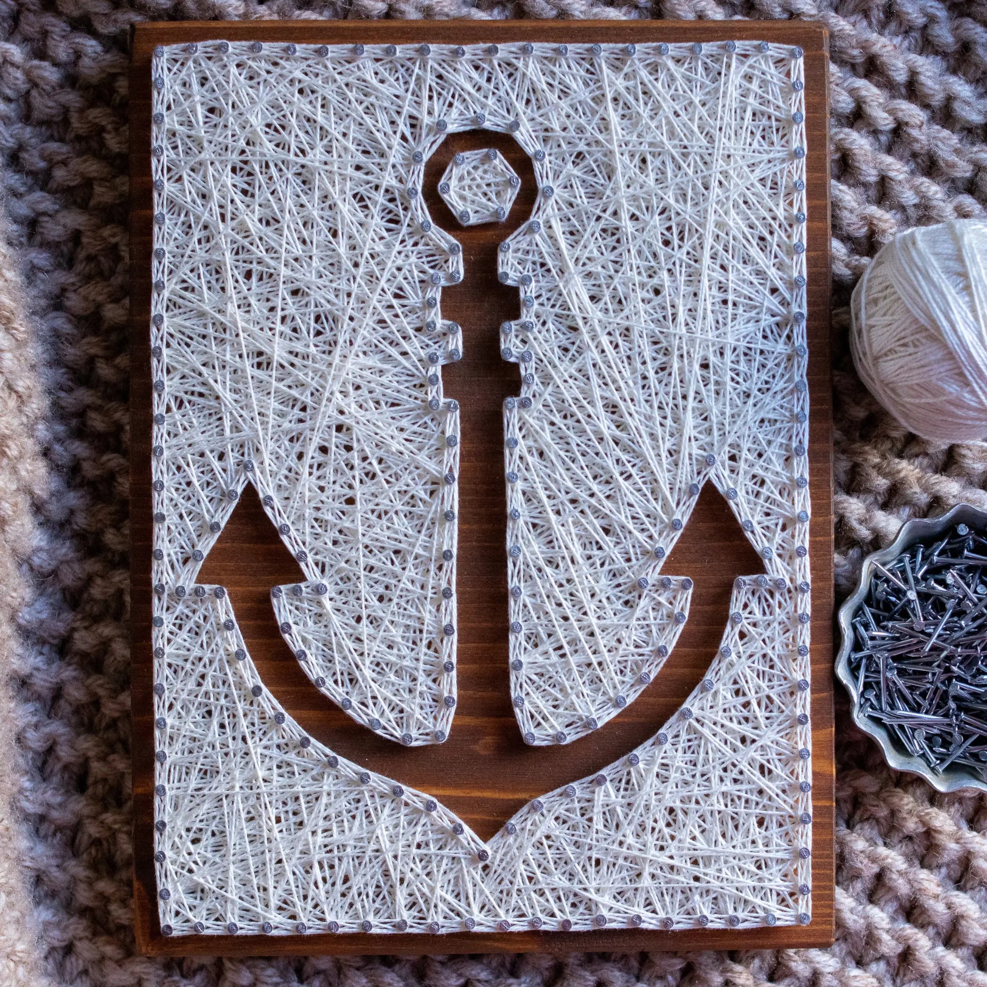 DIY string art kit featuring an anchor outlined with white thread on a rustic wooden board by GoodStrings - top view