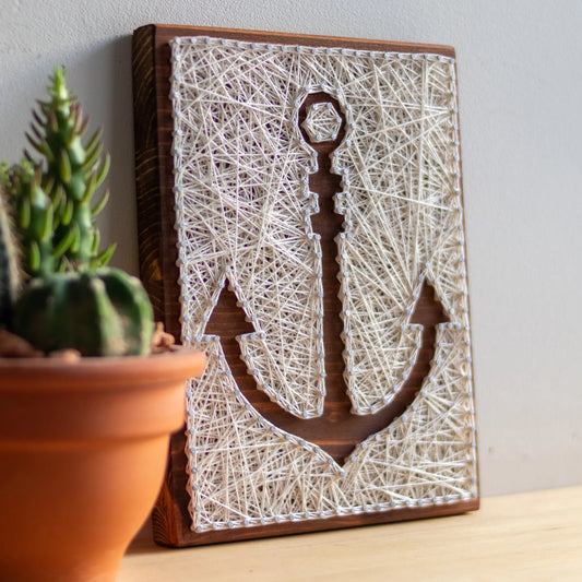 DIY string art kit featuring an anchor outlined with white thread on a rustic wooden board by GoodStrings - side view