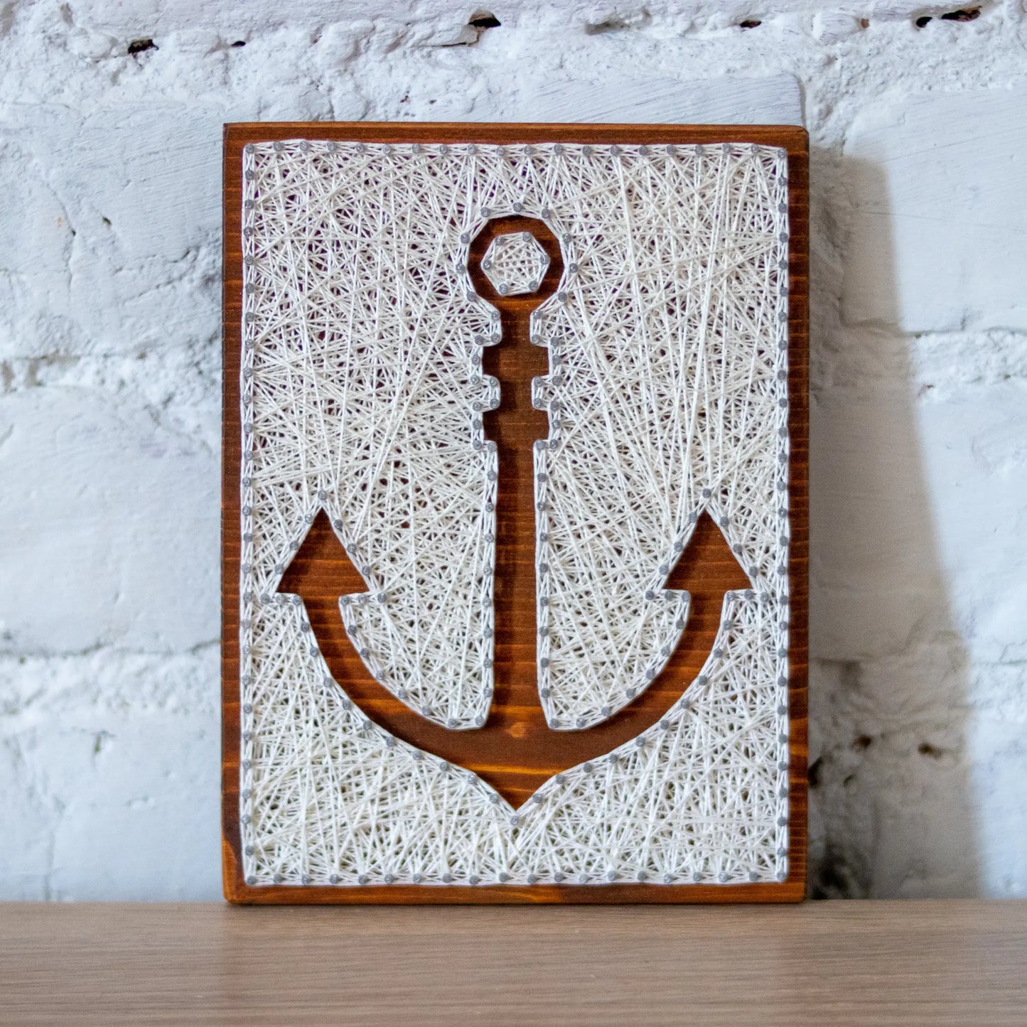 DIY string art kit featuring an anchor outlined with white thread on a rustic wooden board by GoodStrings - from view