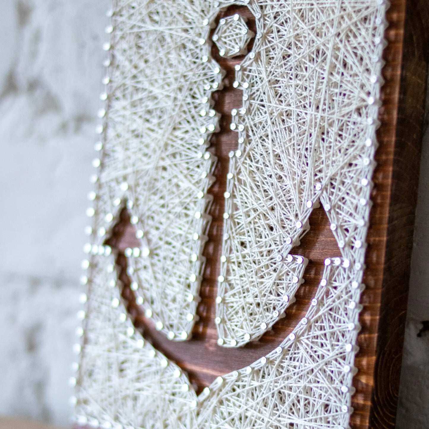 DIY string art kit featuring an anchor outlined with white thread on a rustic wooden board by GoodStrings - details