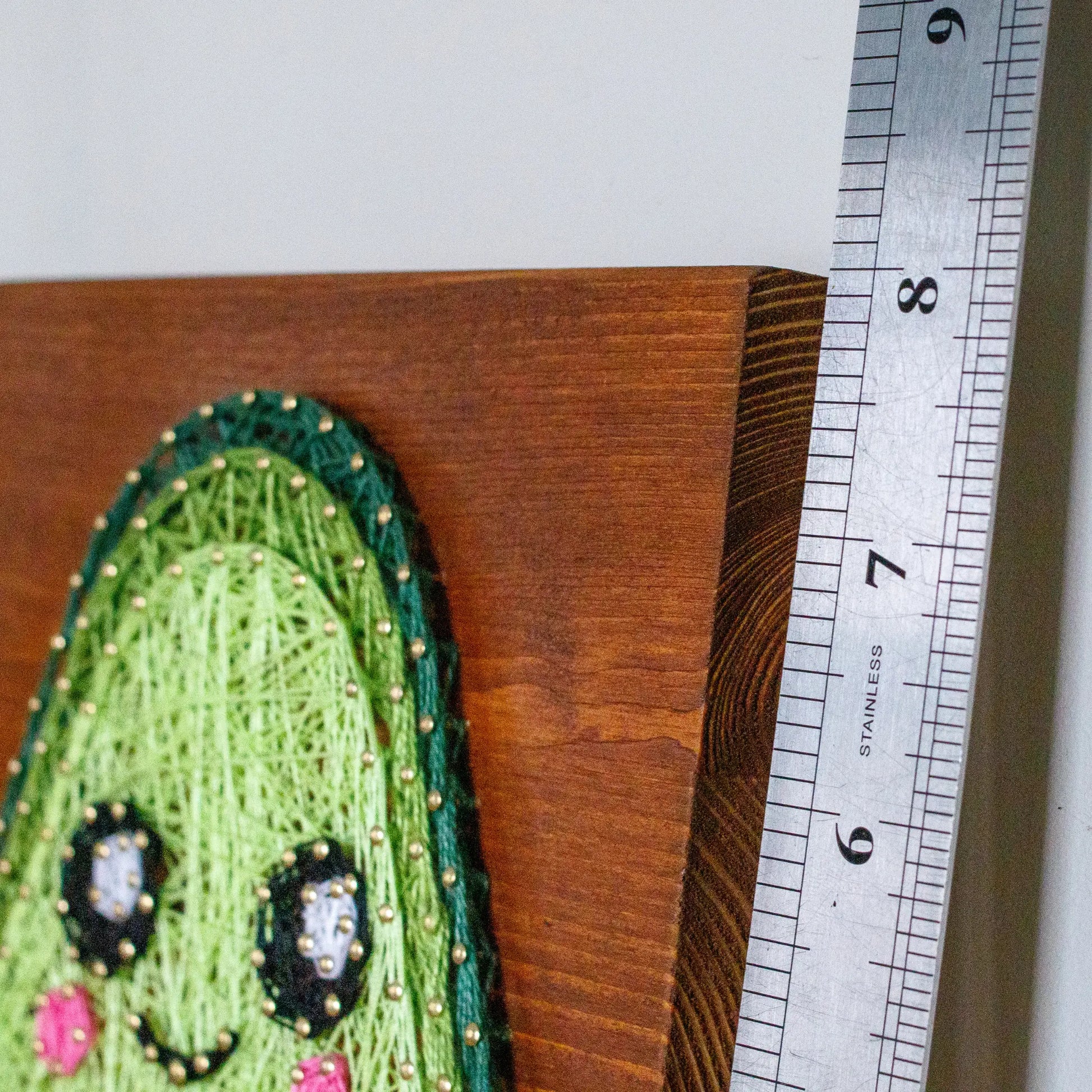 DIY string art kit featuring a cute avocado with a brown heart pit and smiling face created with threads on a wooden board by GoodStrings