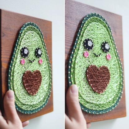 DIY string art kit featuring a cute avocado with a brown heart pit and smiling face created with threads on a wooden board by GoodStrings