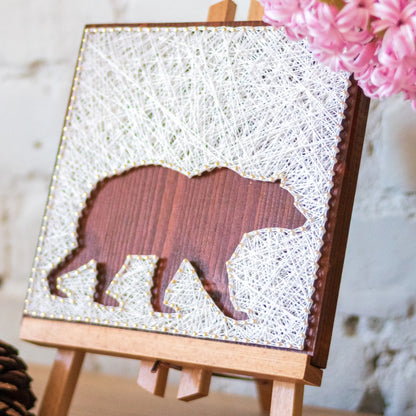 DIY string art kit featuring a bear silhouette with white threads on a dark wooden board by GoodStrings